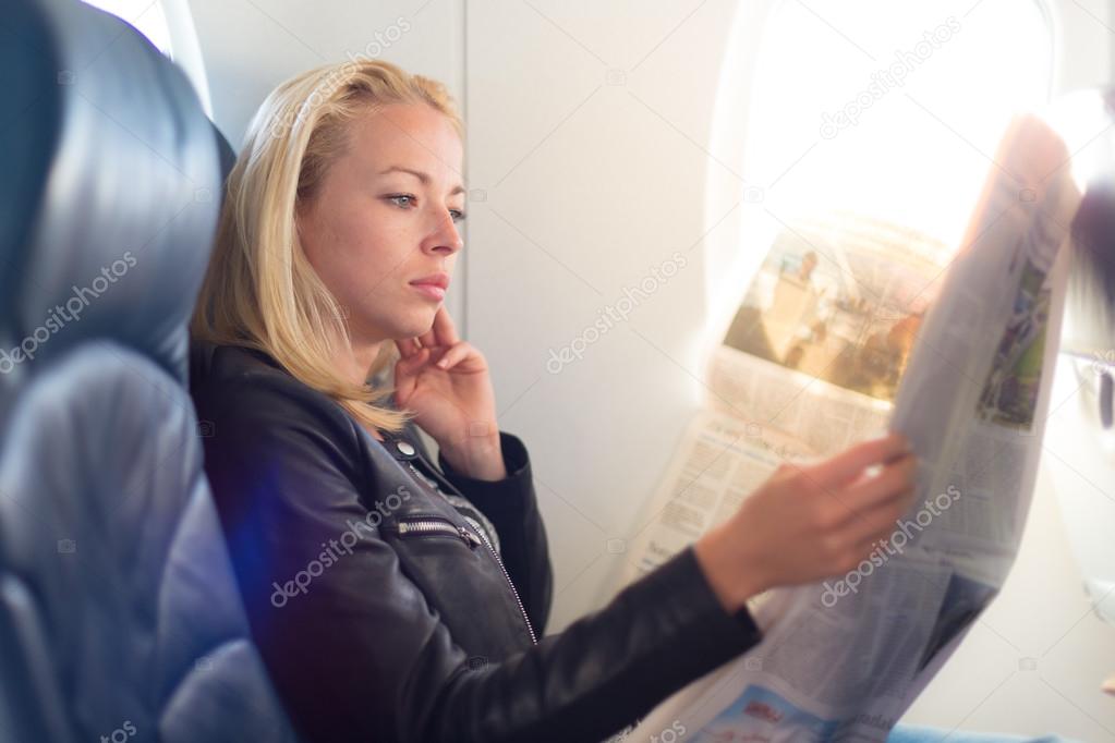 Woman reading newspaper on airplane.