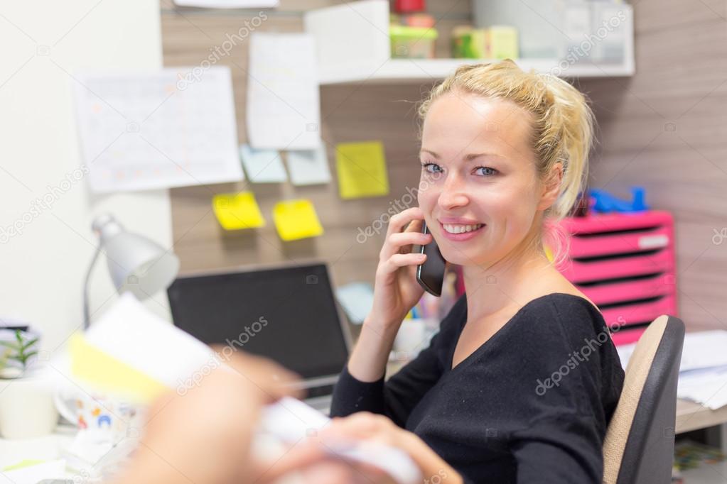 Businesswoman talking on mobile phone in office.