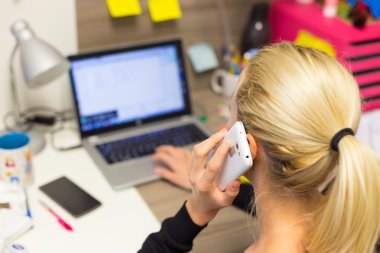 İş kadını ofiste cep telefonuyla konuşuyor..