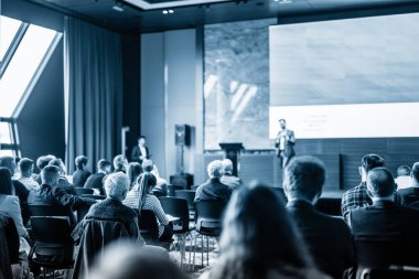 Sözcü, iş konferansında konferans salonunda konuşma yapacak. Mavi tonlu siyah beyaz resim