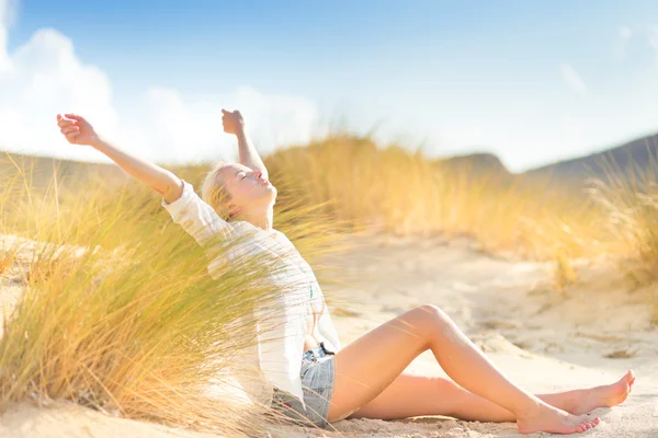 Woman relaxing on sand dunes.