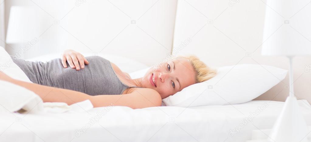 Young woman waking up with smile on face.