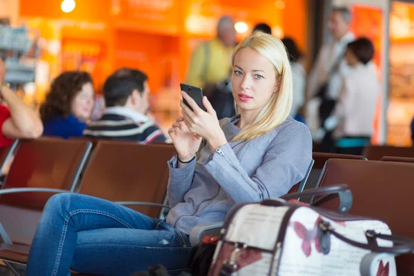 Kvinnliga resenären använder mobiltelefon medan du väntar. — Stockfoto