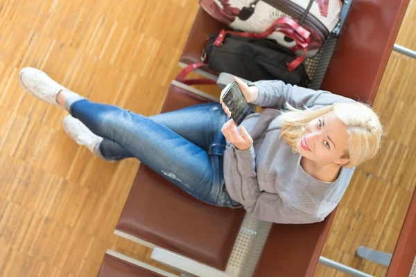 Vrouwelijke reiziger met behulp van mobiele telefoon terwijl we wachten. — Stockfoto