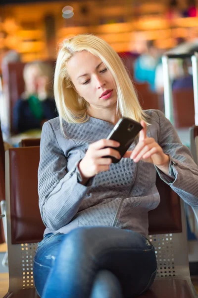 Viajero femenino usando el teléfono celular mientras espera . —  Fotos de Stock