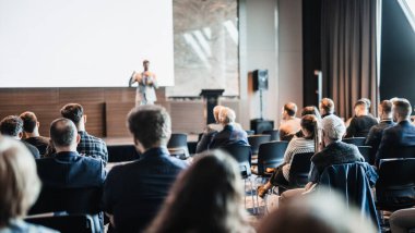 Sözcü, iş konferansında konferans salonunda konuşma yapacak. Konferans salonundaki tanınmayan insanların arka görüntüsü. İş ve girişimcilik kavramı