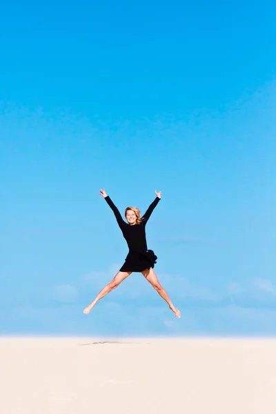 Girl jumping in the air on sand dune. — Stock Photo, Image