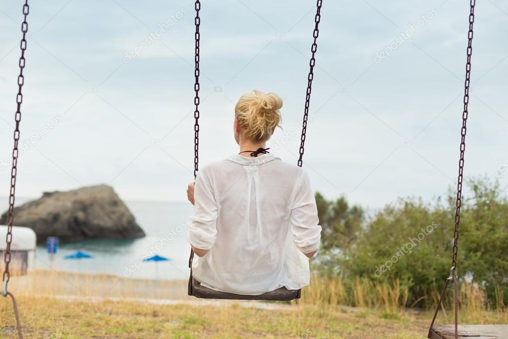 Young blonde woman sitting on the swing