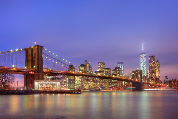 Brooklyn bridge and New York City Manhattan downtown skyline at dusk with skyscrapers illuminated over East River panorama. Copy space.