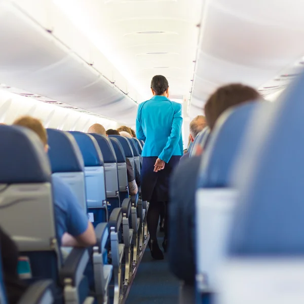 Interior do avião com aeromoça caminhando pelo corredor . — Fotografia de Stock