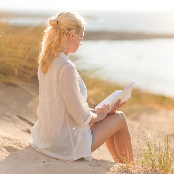Kobieta jest czytanie na pięknej, piaszczystej plaży. — Zdjęcie stockowe