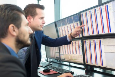 Stock traders looking at computer screens. clipart