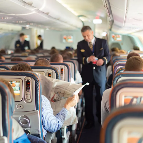 Mayordomo y pasajeros en avión comercial . — Foto de Stock