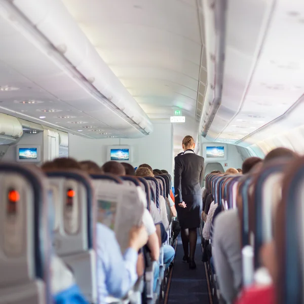 Aeromoça e passageiros em avião comercial . — Fotografia de Stock