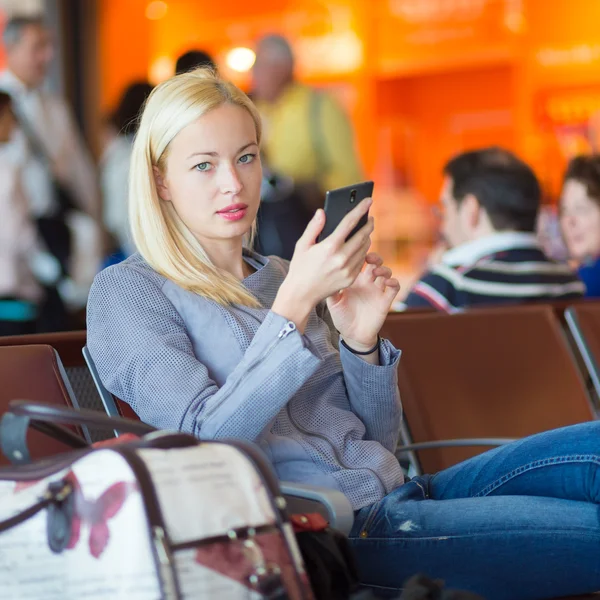 Viaggiatore femminile utilizzando il telefono cellulare durante l'attesa . — Foto Stock