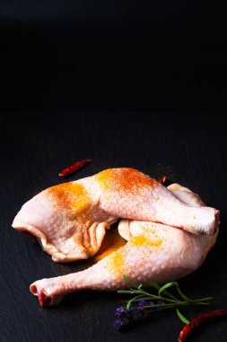 Yiyecek konsepti çiğ tavuk çeyreklikleri. Siyah tahta üzerinde baharatlar ve fotokopi alanı. 