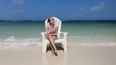Muhteşem kız kumsalda sandalyede dinleniyor. Yaz tatili