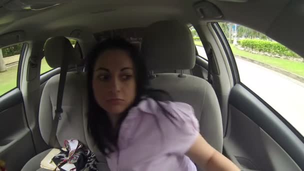 Femme à la recherche de vêtements dans la voiture en conduisant . — Video