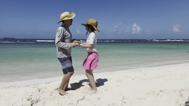Father teaching her daughter to dance salsa in the beach. Family and education concept