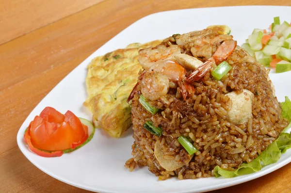 Nasi goreng dengan telur dadar di piring putih di meja kayu — Stok Foto