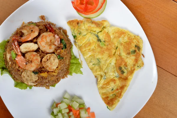 Fried rice with omelet on white plate at wooden table — Stock Photo, Image