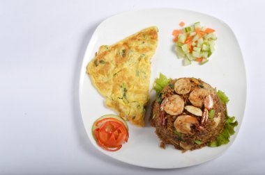 Tahta masadaki beyaz tabakta omletli kızarmış pirinç.