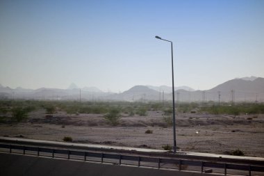 Uzak dağlar ve ıssız bir sokak lambası ile kurak araziyi keşfetmek, seyahat, çevre ve altyapı temalı projeler için mükemmeldir. Suudi Arabistan 'ın Medine şehrinde.
