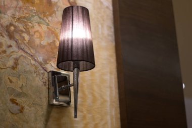 Sconce ışıklandırması, dokulu taş bir duvara karşı sıcak bir parıltı sunuyor. Zarif alanlar için modern tasarım.