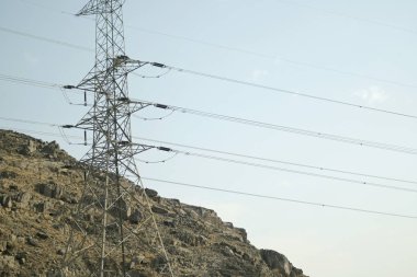 Gökyüzüne uzanan çoklu güç hatları ile devasa elektrik iletim kulesi endüstriyel ilerlemeyi ve enerji dağılımını simgeliyor..