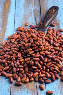 Mavi ahşap masa üstünde tahta kaşıkla kırmızı fasulye