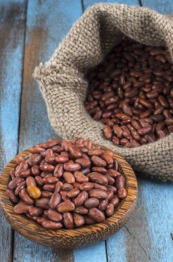 Mavi ahşap masa üstünde tahta kaşıkla kırmızı fasulye