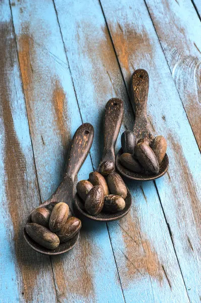 Gałka muszkatołowa na drewnianą łyżką w niebieskim drewnianym stole — Zdjęcie stockowe