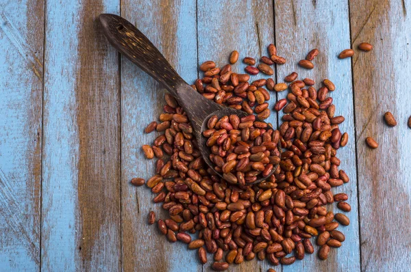 Rote Bohnen mit Kochlöffel auf dem blauen Holztisch — Stockfoto