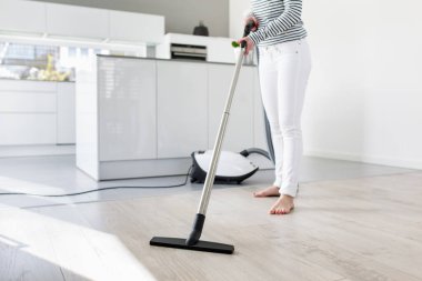 Mutfakta süpürge kullanan kadın.