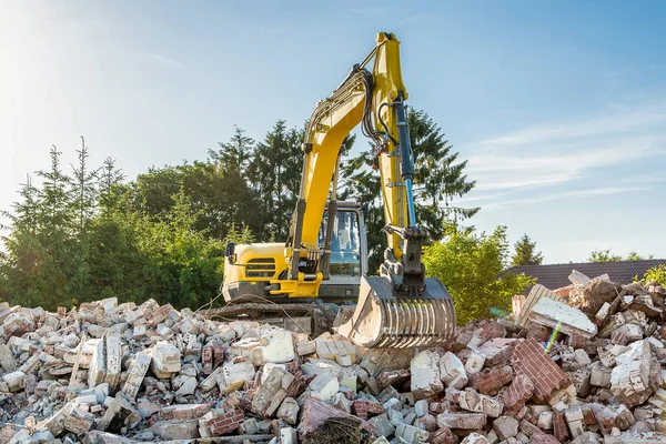 Yellow excavator on top of  construction waste