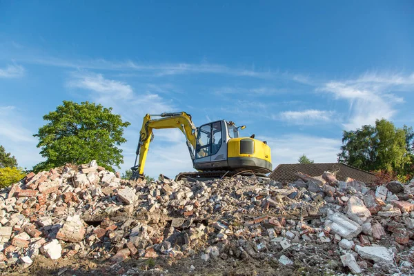 Yellow excavator on top of  construction waste