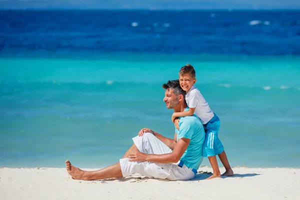 Far och son leker på stranden. — Stockfoto