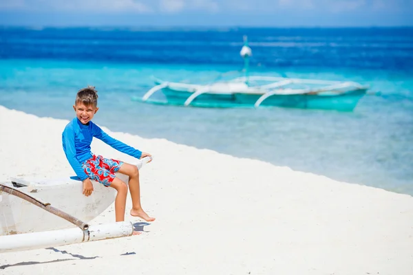 Menino sentado em barco velho na praia — Fotografia de Stock