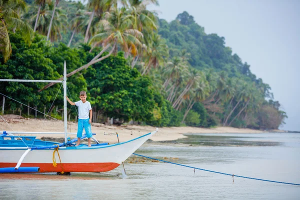 Niño en barco viejo en la playa — Foto de Stock