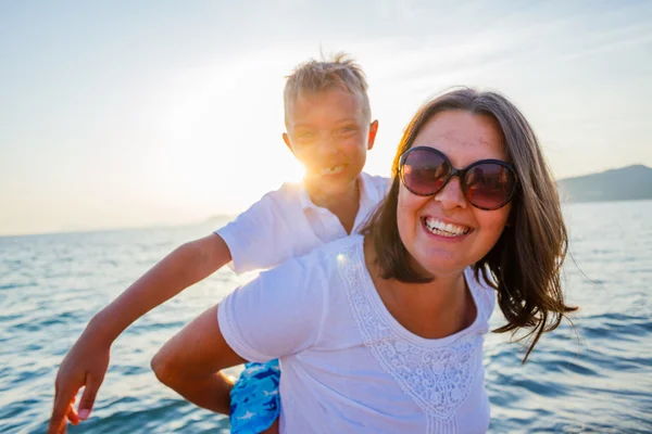 Mor och son leker på stranden. — Stockfoto