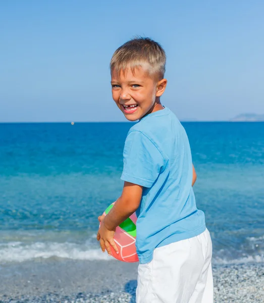 Хлопчик грає в м'яч на пляжі — стокове фото