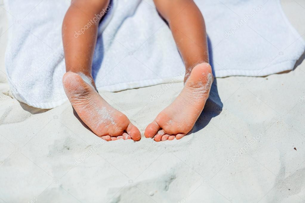 Child feet on beach towel