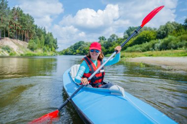 Mutlu aile yaz tatili boyunca güneşli bir günde nehirde kano yapıyor.