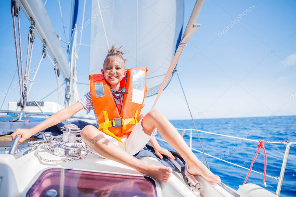 Little boy on board of sailing yacht on summer cruise. Travel adventure, yachting with child on family vacation.