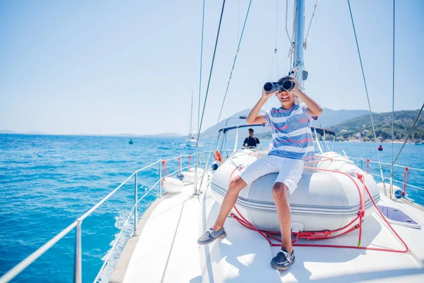 Menino a bordo do iate à vela no cruzeiro de verão. Viagem aventura, iatismo com criança em férias em família. — Fotografia de Stock