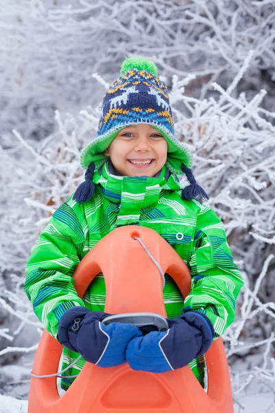 Маленький хлопчик розважається з санчатами в зимовому парку — стокове фото