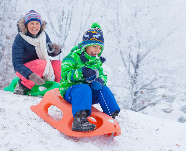 Family having fun with sled in winter park