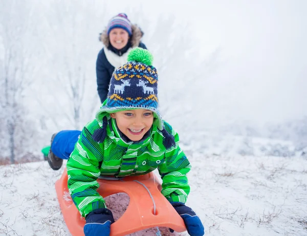 Kleine jongen met plezier met slee in winter park — Stockfoto