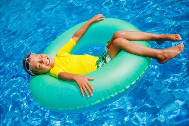 Çocuk bir havuzda yüzüyor