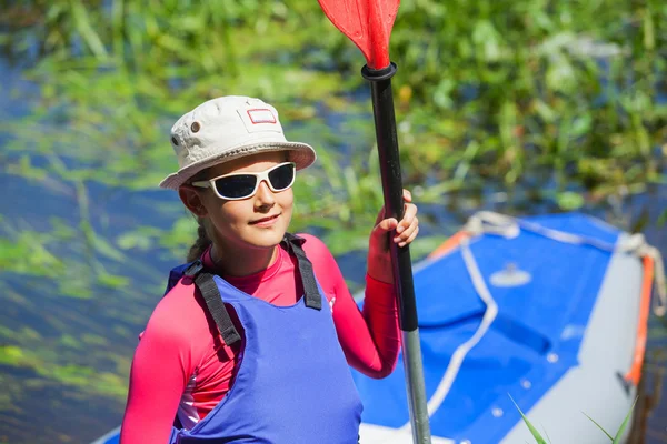 Meisje in de buurt van een kajak op de rivier — Stockfoto